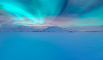 Beautiful landscape cracking ice, frozen norwegian sea coast - Northern lights (Aurora borealis) in the sky over Tromso, Norway