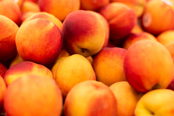 A pile of fresh peaches in the grocery store produce section 