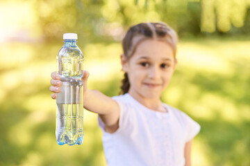 Little girl holding water bottle. Outdoor training. Thirsty. Plastic drink. Summer time. Pretty...