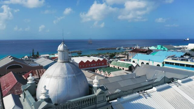 Drone approaches a ship at sea through the city over the roofs, cars, people, the port in Bridgetown, Barbados
