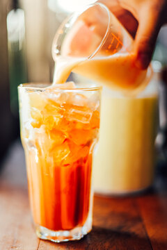 Iced milk thai  tea in glass  on wood table at cafe.