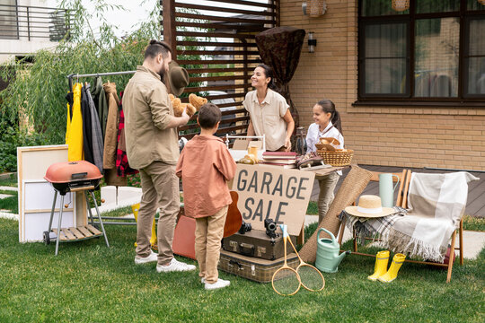 Bearded Man Standing At Table With Various Goods And Asking Seller About Toy Bear While Buying Toy At Yard Sale