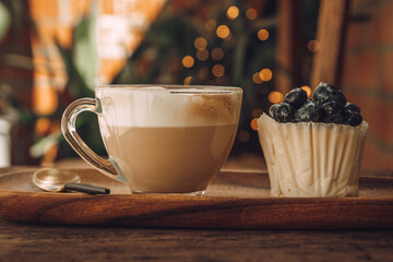  Coffee with milk in a transparent cup and white cupcake with berries