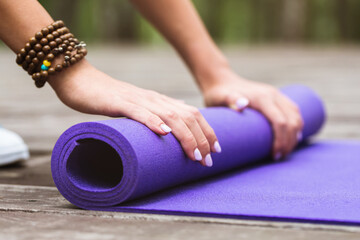 Obraz na płótnie Canvas Girl unwinding gymnastic mat for yoga class outdoors, close-up