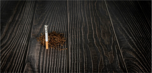 burning cigarette and dried tobacco lay on a wooden background. illness concept.