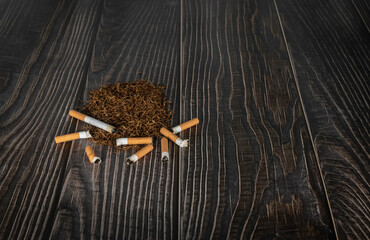 cigarette and cigarette butts on heap of tobacco in a wooden background with copy space.illness concept