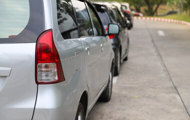 Closeup of rear, back side of bronze minivan  car with  other cars parking in parking area.