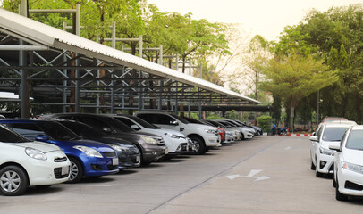 Closeup of front side of white car with other cars parking in indoor parking area with natural background in sunny day. 