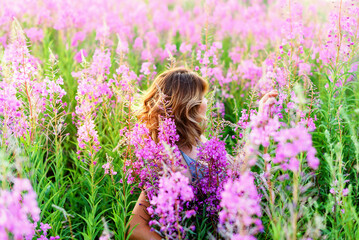 Back view of young woman on fireweed meadow