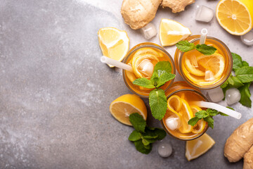 iced tea with lemon, ginger and mint in tall glasses on gray background