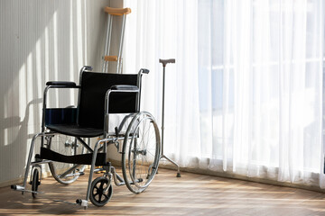 Fototapeta na wymiar Wheelchair in the room near the window with crutch at behind equipment for patients.