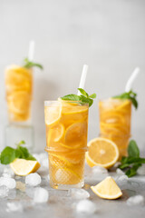 iced tea with lemon, ginger and mint in tall glasses on gray background