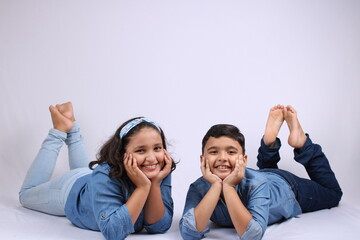 Two cute Indian kids lying over white background.
