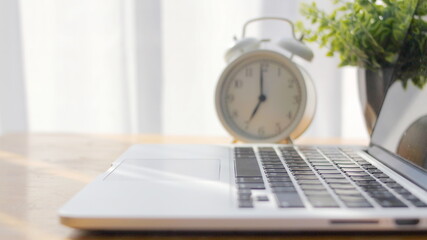 Naklejka premium laptop is placed on the table with an alarm clock.