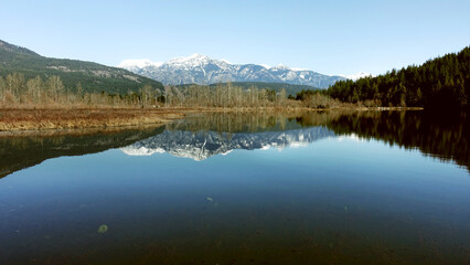 a tranquil scene of One Mile Lake with the reflection of the snow covered mountains in British Columbia Canada, road trip, explore the beauty of local area