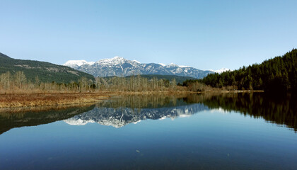 Fototapeta na wymiar a tranquil scene of One Mile Lake with the reflection of the snow covered mountains in British Columbia Canada, road trip, explore the beauty of local area