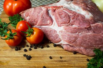 Fresh pork neck meat on a wooden surface near tomatoes parsley onion concept of cooking meat dishes restaurant food steak kebab