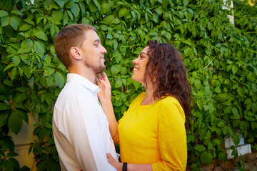 A date between a young girl and a guy on a Sunny summer day. Young beautiful couple on walk in the city. Man and woman at a love meeting with hugs and kisses outdoors