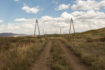 Summer steppe landscape. Landscape in kazakhstan. Kazakh steppe. Blue sky. Yellow grass. Country road. Forest Steppe. Green trees. Power line