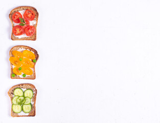 Breakfast sandwiches with vegetable veggie toppings and cream cheese on white background copy space