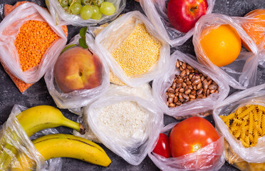 Cereals, fruits and vegetables in plastic bags on a dark table