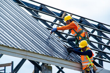 Construction worker install new roof at construction site,Electric drill used on new roofs with Metal Sheet. © visoot