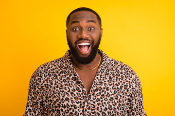 Photo of crazy surprised funny dark skin guy tourist summer vacation trip toothy smile open mouth wear golden chain trend leopard shirt isolated bright yellow background