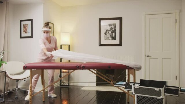 Esthetician preparing a massage table using disposable products. Covid safe environment  
