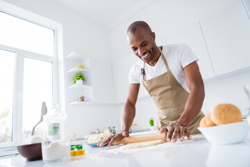 Portrait of his he nice attractive cheerful guy making handmade bread pizza pie cake rolling dough enjoying hobby free time in modern light white interior house kitchen