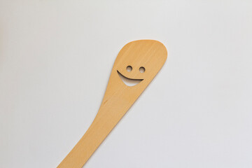 a wooden spatula with a cut-out smile isolated on a white background kitchen utensils