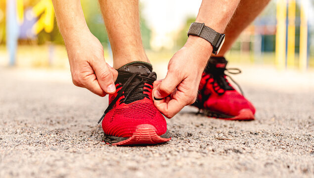 Man tying shoelace on red sneakers