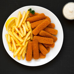 Homemade Fish Sticks and Fries with Tartar Sauce on black surface, top view. Flat lay, overhead, from above.