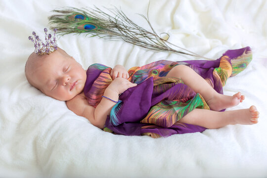 Cute newborn baby girl is sleeping. A newborn Princess in a crown and a beautiful purple dress is sleeping sweetly.
