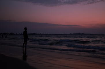 Man enjoying the sunset at a beach. The sky is very vibrant after the sun is set. 