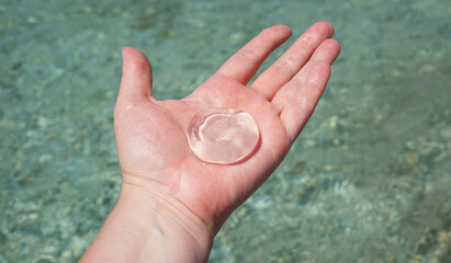 Round jellyfish on the palm of the hand against the background of sea water. Arm. Hands. Round shapes in nature.