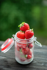 Fresh strawberries in a can in nature on a black wooden window sill.