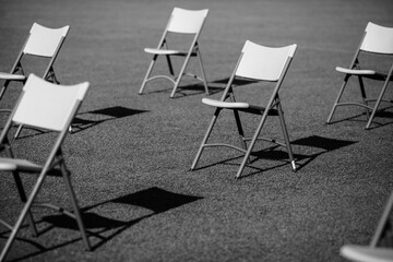 Chairs apart one from another to maintain the social distance during the Covid-19 outbreak at an outdoor event on the turf of a stadium.