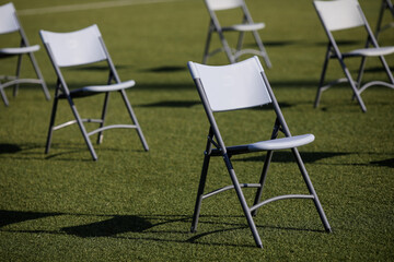 Chairs apart one from another to maintain the social distance during the Covid-19 outbreak at an outdoor event on the turf of a stadium.