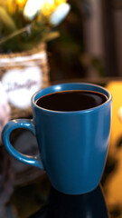 Evening coffee. Blue cup with coffee, open book and mobile phone, evening light, sunset, dusk. Atmospheric, cozy evening in the garden, green leaves, conversation. Warm light, blur bokeh.