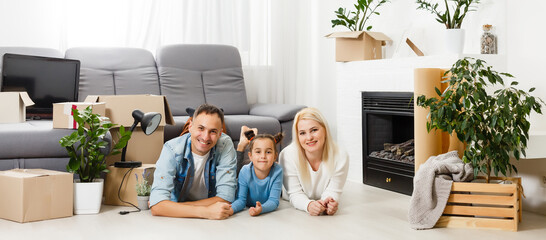Happy family sitting on wooden floor. Father, mother and child having fun together. Moving house...