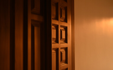 Evening sunlight falls on the wooden door which is contemporary styled and contain carvings on it.