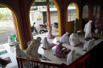 Muslim women praying inside the mosque wearing masks and maintaining social distancing according to health protocols.