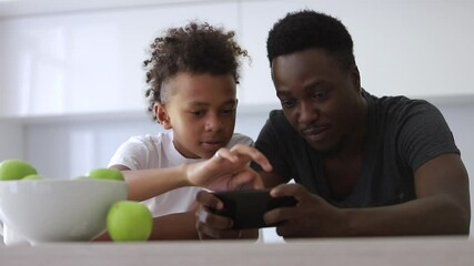 teen son and dad use phone together. Spbi watch cartoons, play games. concept technology and smartphone addicted. loving afro and mixed race family. bonding, communication with father - Powered by Adobe