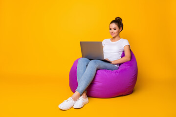 Naklejka premium Full size photo of focused smart girl sit purple bag bean work computer read colleagues report document wear style stylish trendy sneakers isolated over bright shine color background