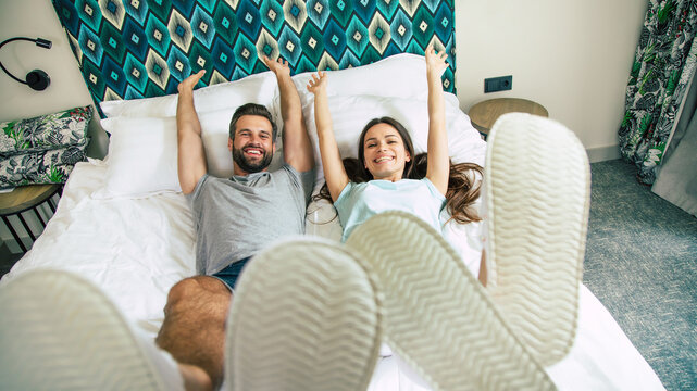 Top view photo of the funny excited happy couple in love are lying on the bed in a hotel room and having fun together