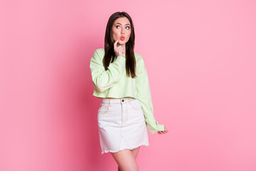 Photo of attractive funny lady look wondered side empty space finger on chin cheek brainstorming wear casual green crop pullover jeans mini skirt isolated pink pastel color background
