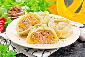 Manty with meat and pumpkin in plate on dark board