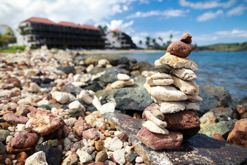 Stones balance on beach and behind hotel resort in blur 