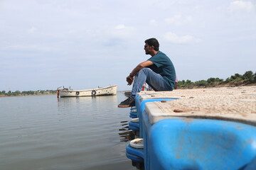 Young Dark Indian Man Sitting on the lake Water