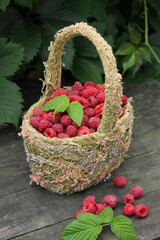 Fototapeta na wymiar Berries. Fresh raspberries in a basket on an old grey wooden table with leaves. Rustic. Summer, garden, outdoor. Harvest. Background image, copy space